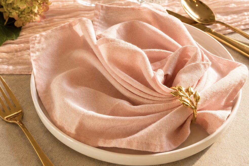 Hochzeitsdeko mieten Tischgedeck mit Tellern, Besteck und gefalteter Serviette auf einem eleganten Tisch.